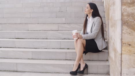 Grinsende-Frau-Auf-Der-Treppe,-Die-Kaffee-Trinkt