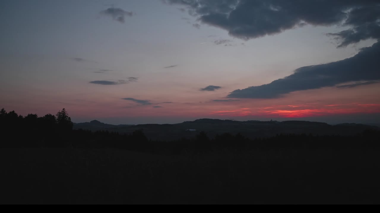 Timelapse of calm sunset with trees and hills on the horizon