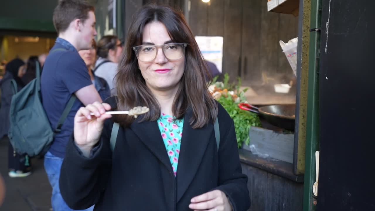 Woman samples risotto at bustling Borough Market food stall in London