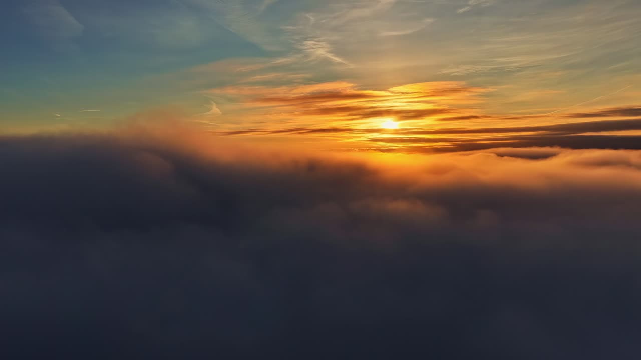 Golden sunset light spills across a sea of clouds, creating a soft, glowing horizon as warm colors blend into the evening sky