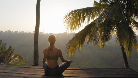 yoga woman meditating at sunrise practicing mindfulness meditation exercise sitting on deck outdoors in nature 4k