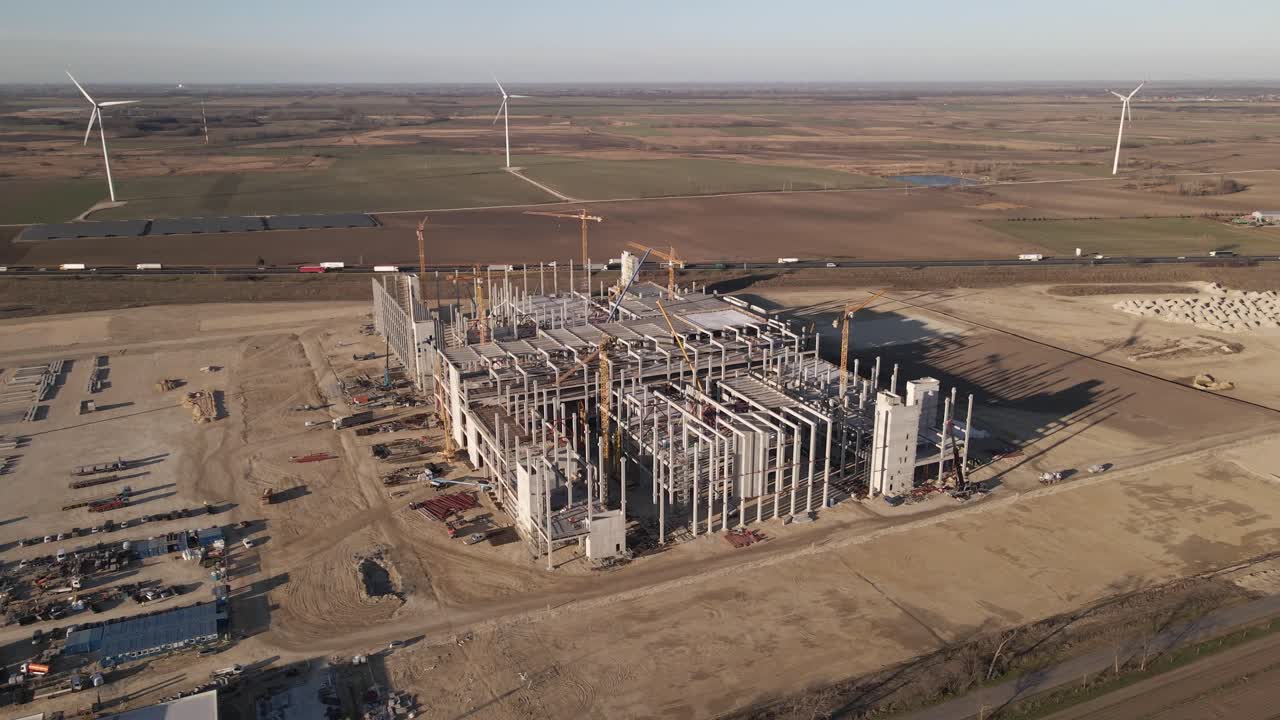 Drone flying around a Large Industrial Construction Site, next to the highway with moving trucks and cars.