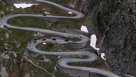 incredible aerial view of row of cars driving along extremely dangerous winding tremola paved mountain road in switzerland