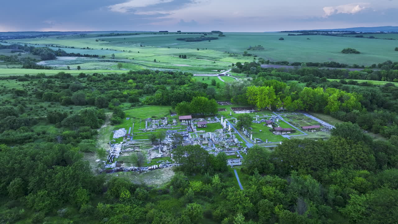 Drone orbit over Nicopolis ad Istrum as the ancient Roman city remains lie in shadow beneath a moody sunset sky