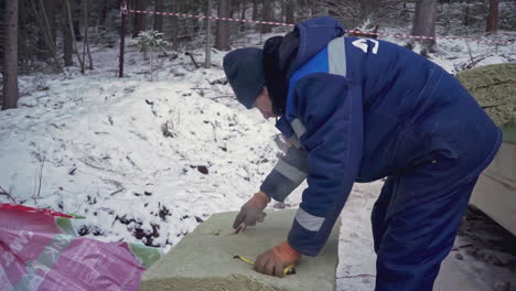 construction worker measuring insulation blocks in winter