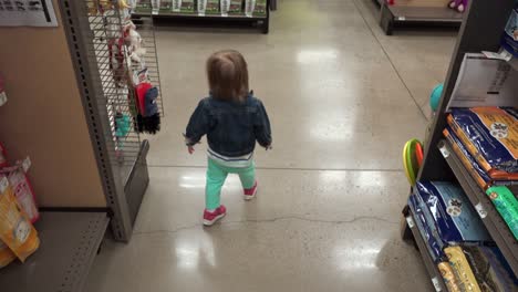 siguiendo a jean jacket toddler en la tienda de mascotas a través del pasillo de comida seca para perros.