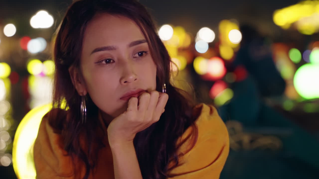 노란색 아오 다이를 입은 젊은 여성이 생각에 빠져 호이안의 배에서, 활기찬 보케 조명