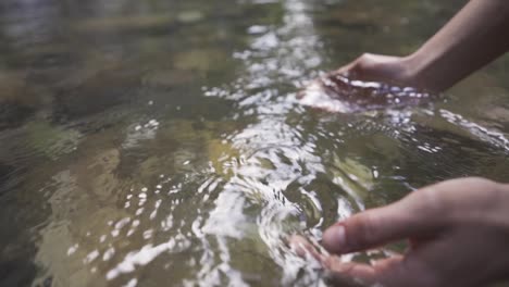 The-hand-that-picks-up-the-water-in-the-stream.-Slow-motion.