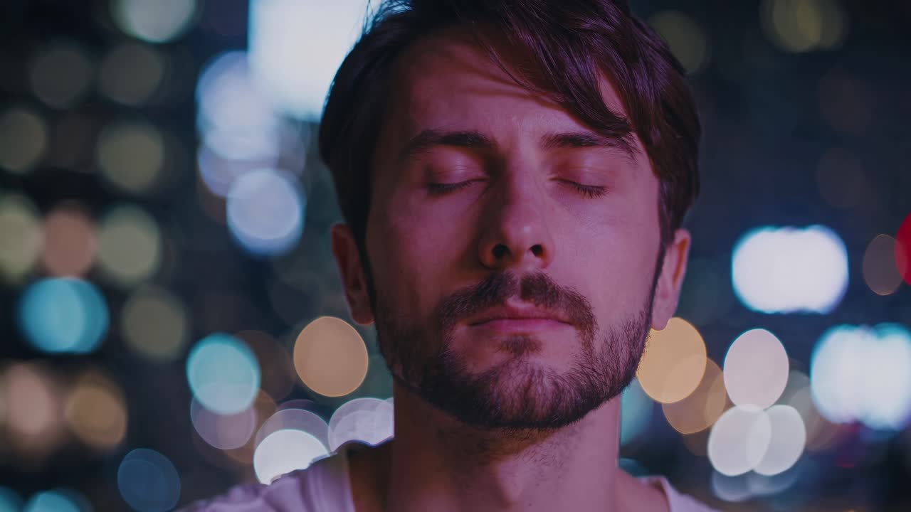 Man with closed eyes experiences tranquility amidst vibrant city lights, showcasing a serene moment of reflection and inner peace in a bustling environment