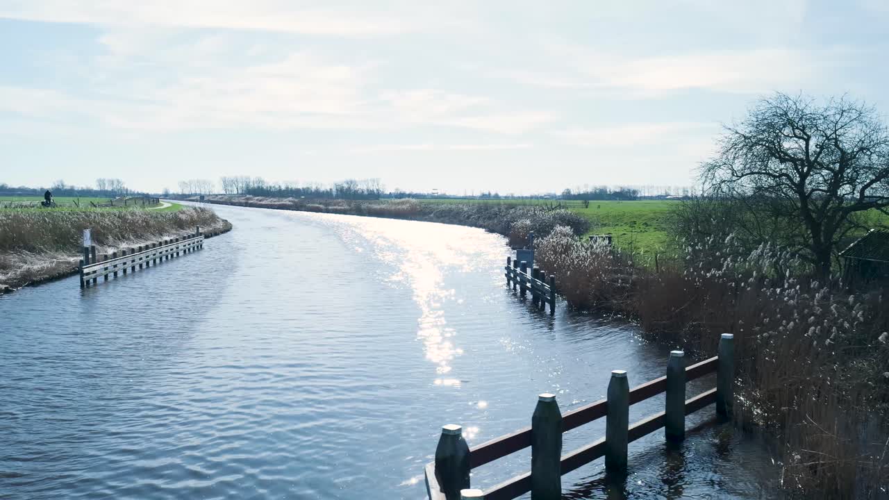 Fredelig kanal i landskab med solens genspejling i vandet