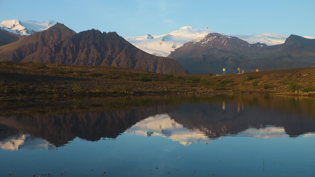 Iceland's calm mountain landscape with clear reflection in water, warm sunlight, serene dawn ambiance