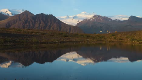 el tranquilo paisaje montañoso de islandia con un claro reflejo en el agua, la cálida luz del sol, el ambiente sereno del amanecer