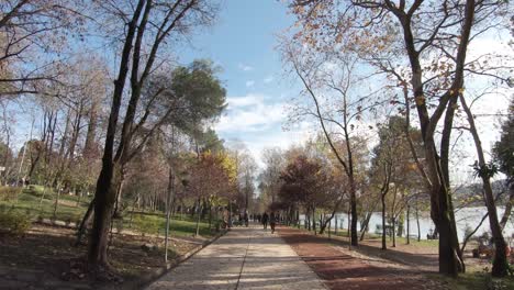 walkway leisure path crossing tirana's grand park alongside the artificial lake in albania - wide push in dolly shot