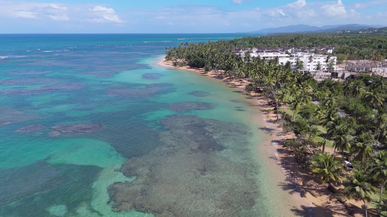 Playa El Portillo beach, crystal waters, coral reef, tropical palm trees, resort beachfront, for vacation and travel promotions, Las Terrenas in Dominican Republic. Aerial forward tilt-up reveal
