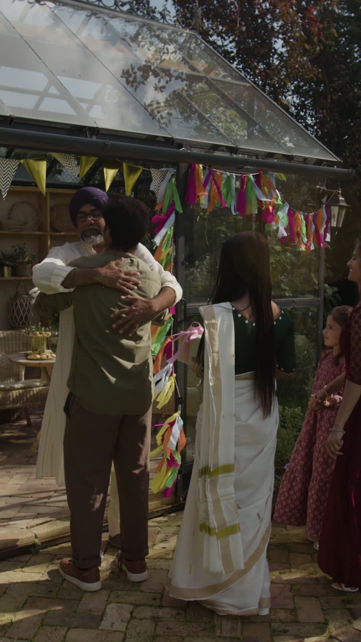 Family and friends celebrate a festival with hugs and conversations in a decorated greenhouse