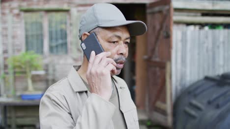 African-american-male-gardener-using-smartphone-at-garden-center