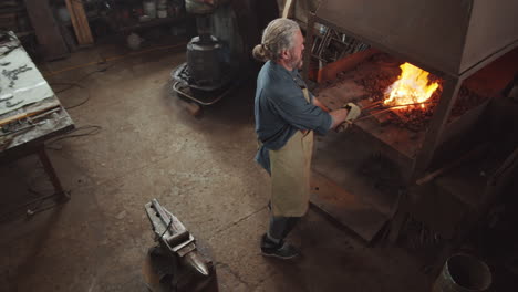 blacksmith tending forge fire in smithy