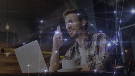 remote worker typing on laptop holding smartphone in tech cafe, showing glowing network overlay