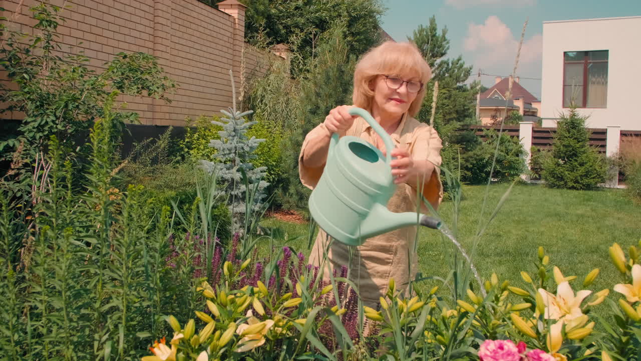 Senior Woman Watering Flowers In Yard