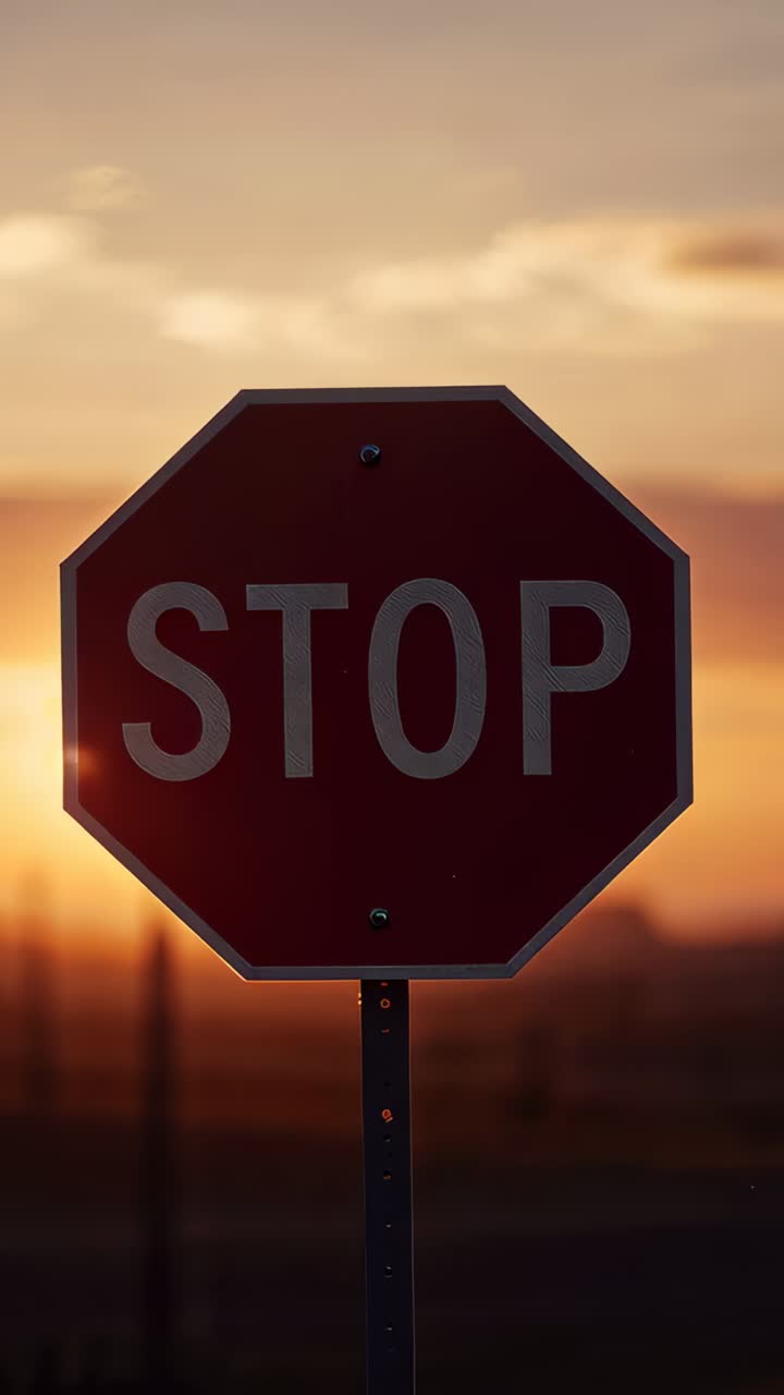 Vertical video: Camera filming red octagon STOP sign at roadside sunset, sun moving, flare shifting