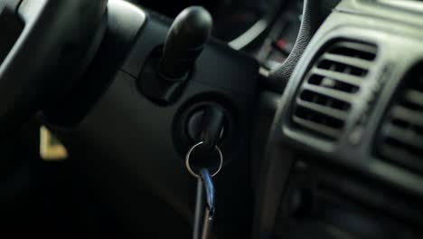 Close-up-shot-of-hand-turning-key-inside-car-and-starting-engine