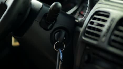 close up shot of hand turning key inside car and starting engine