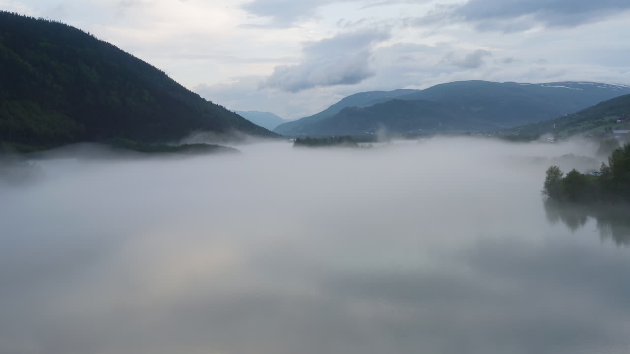 Flight over a foggy river. The mist is hanging low over the landscape creating a dark mystical mood over the whole scene.