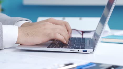 dedos escribiendo en el teclado en el portátil en la oficina de primer plano.