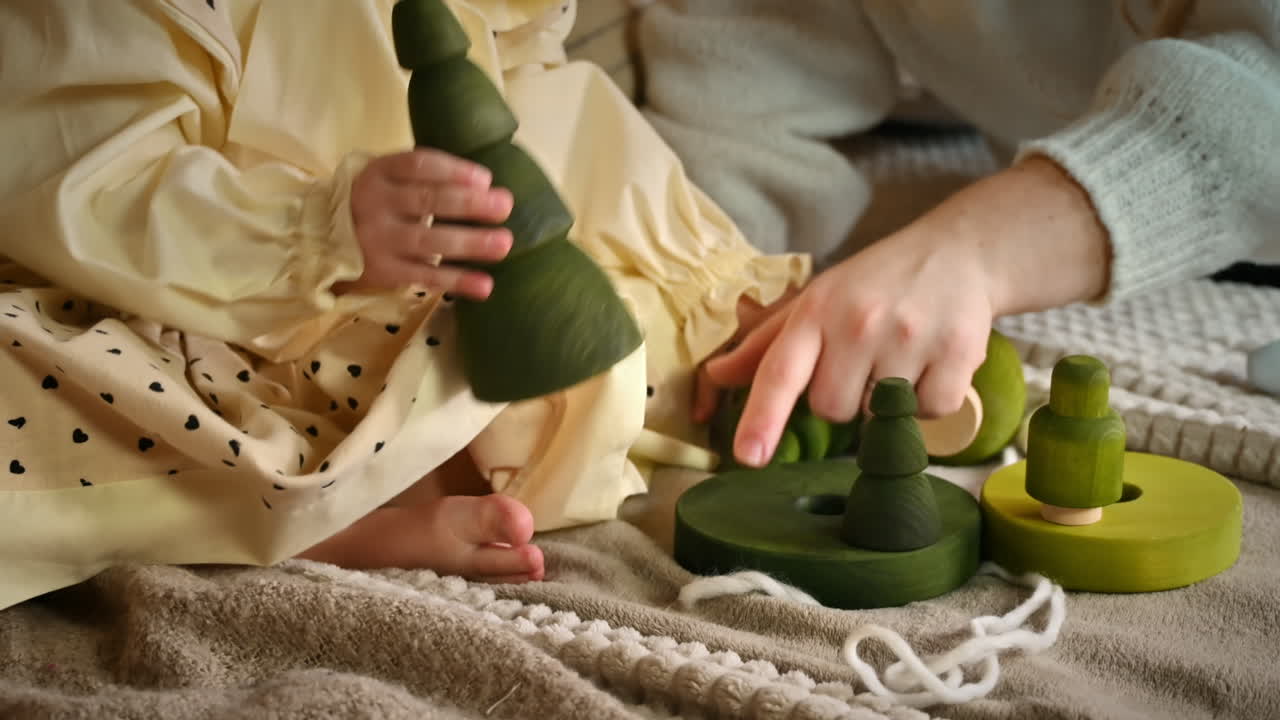 Little girl and her mother playing with several wooden tree toys. Ecological and sustainability concept