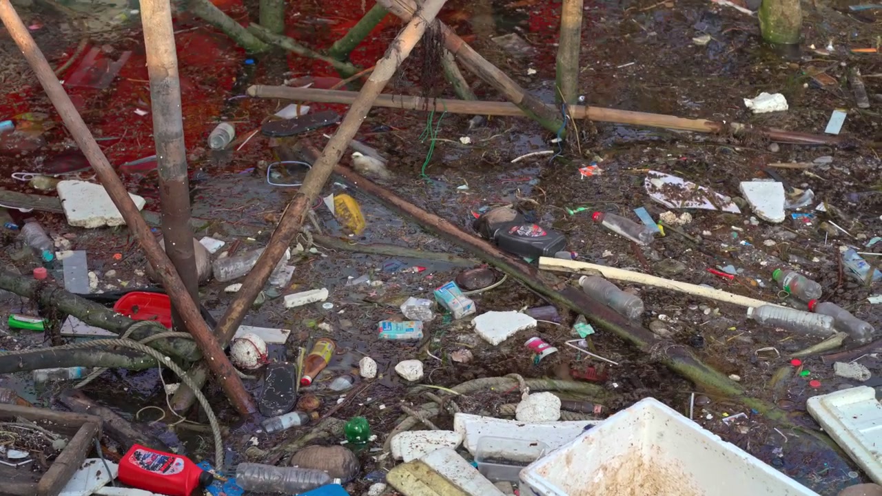 Rifiuti di plastica e detriti che inquinano un corso d'acqua poco profondo