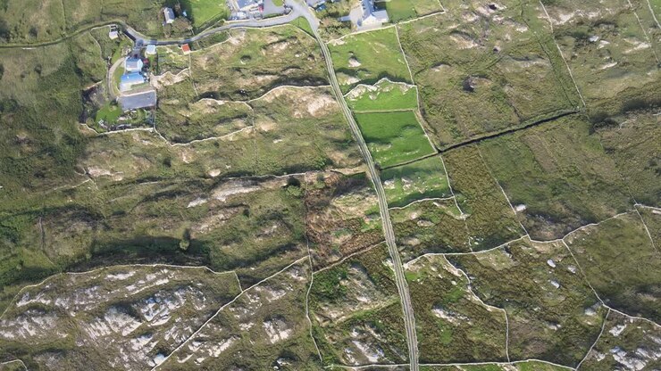 Lush Farmland Surrounded By Rocky Fields In Connemara, Ireland On A Sunny Day - top-down aerial shot