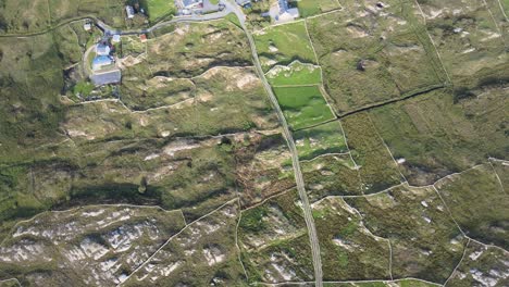 Lush-Farmland-Surrounded-By-Rocky-Fields-In-Connemara,-Ireland-On-A-Sunny-Day---top-down-aerial-shot