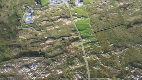 exuberantes tierras de cultivo rodeadas de campos rocosos en connemara, irlanda en un día soleado - toma aérea de arriba hacia abajo