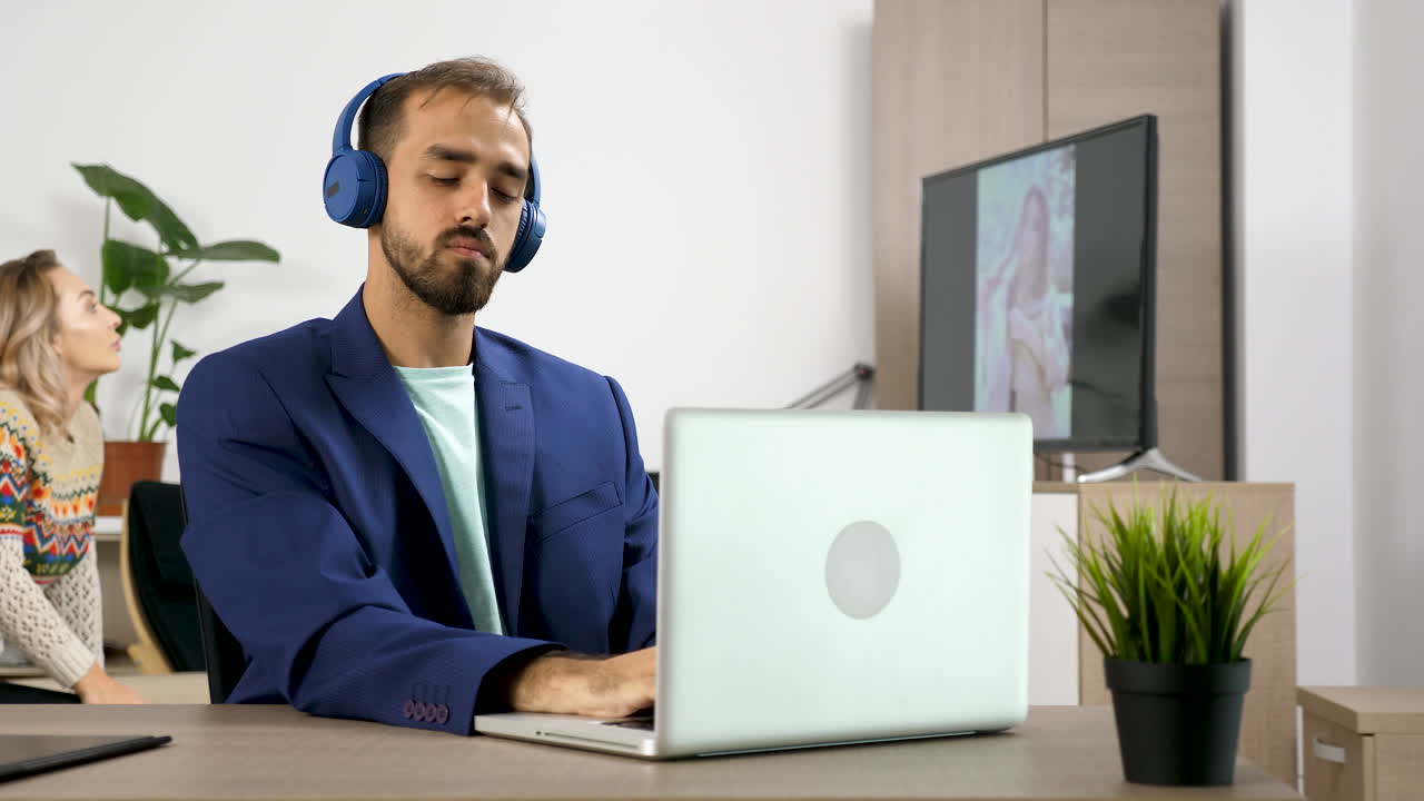 Man working on laptop while woman watches television