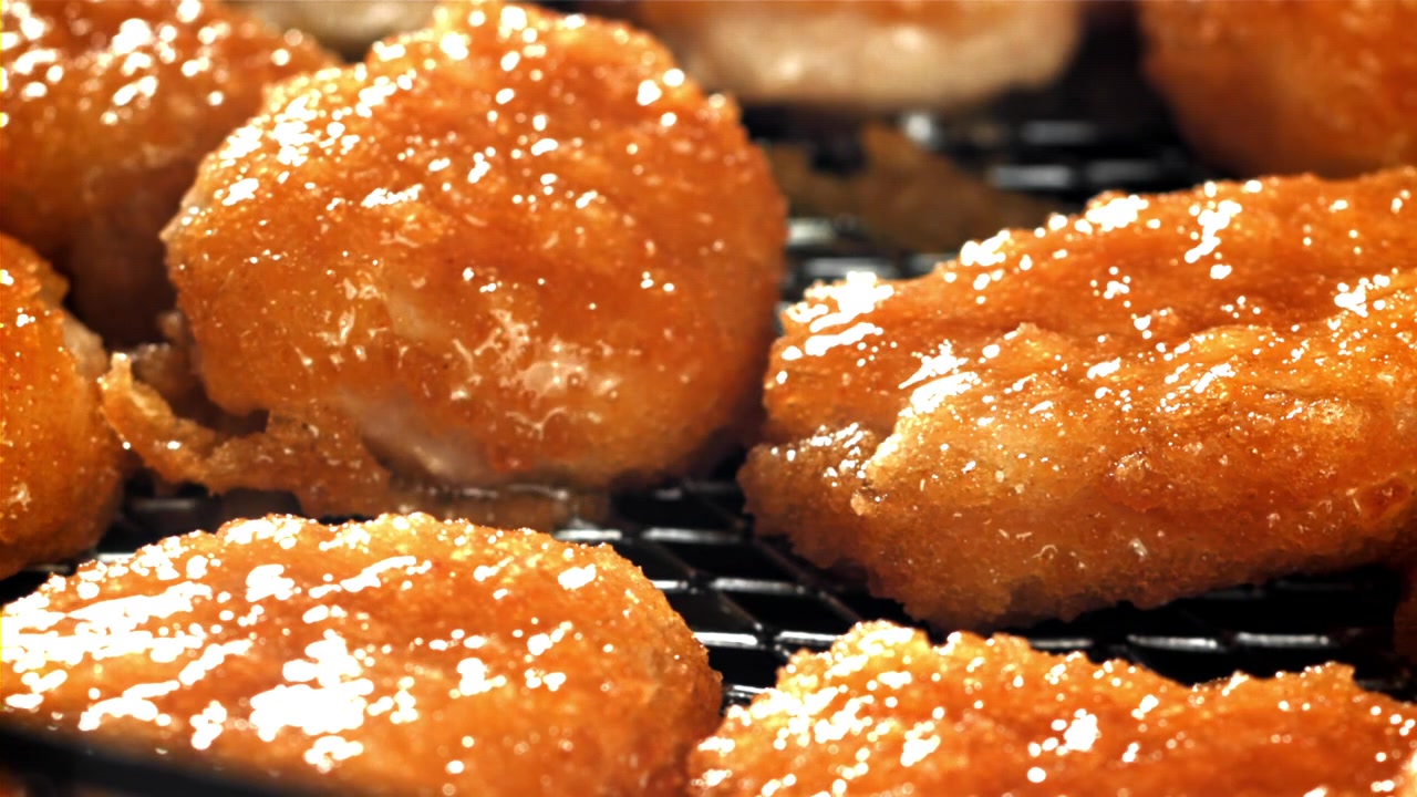 冷却ラックに並べられた、焼きたてでグレーズがけされたきつね色のドーナツのクローズアップ。