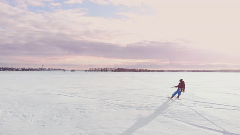 4K-aerial-winter-extreme-sport-snow-kiting-competition-race-with-different-colorful-snow-kites,-ski,-snowboarders-over-the-ice-lake-in-front-of-city-at-blizzard-and-snow-weather-from-drone