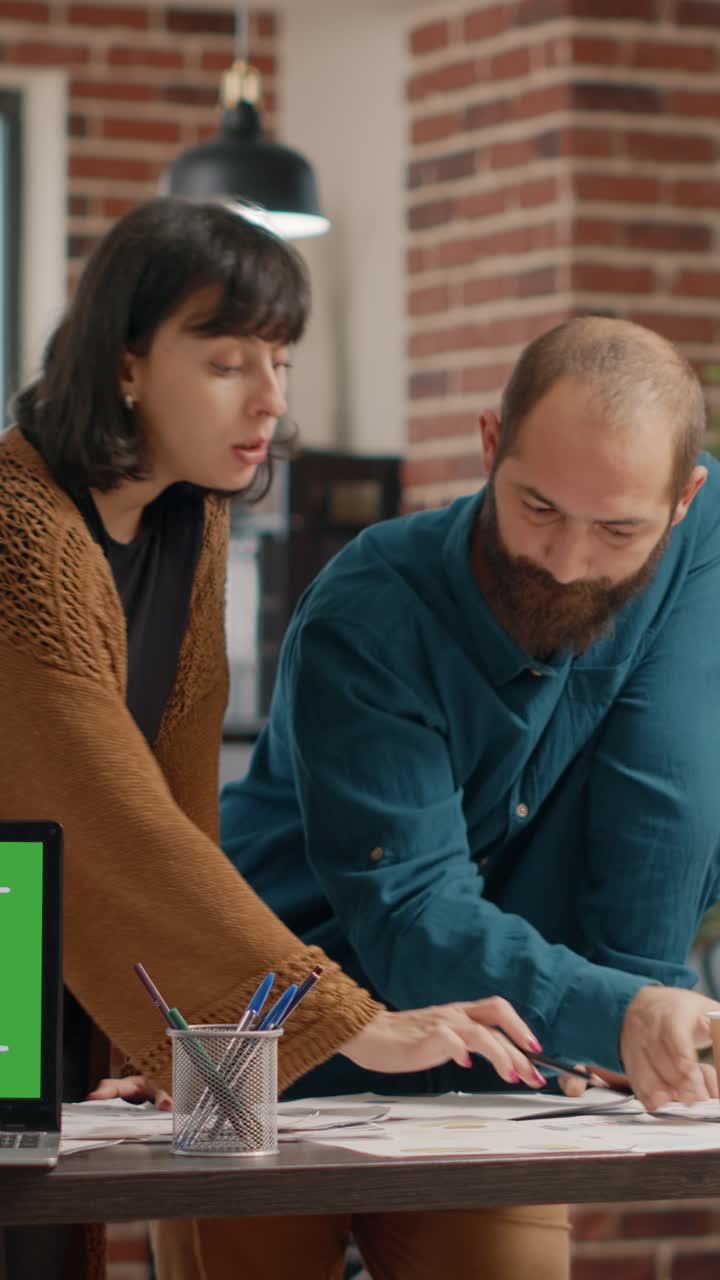 Team collaborating on a project with green screen laptop in the office