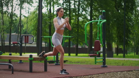 una joven y hermosa mujer sola realiza ejercicios en el parque en verano en un banco. estilo de vida saludable y entrenamiento deportivo en el parque en verano.