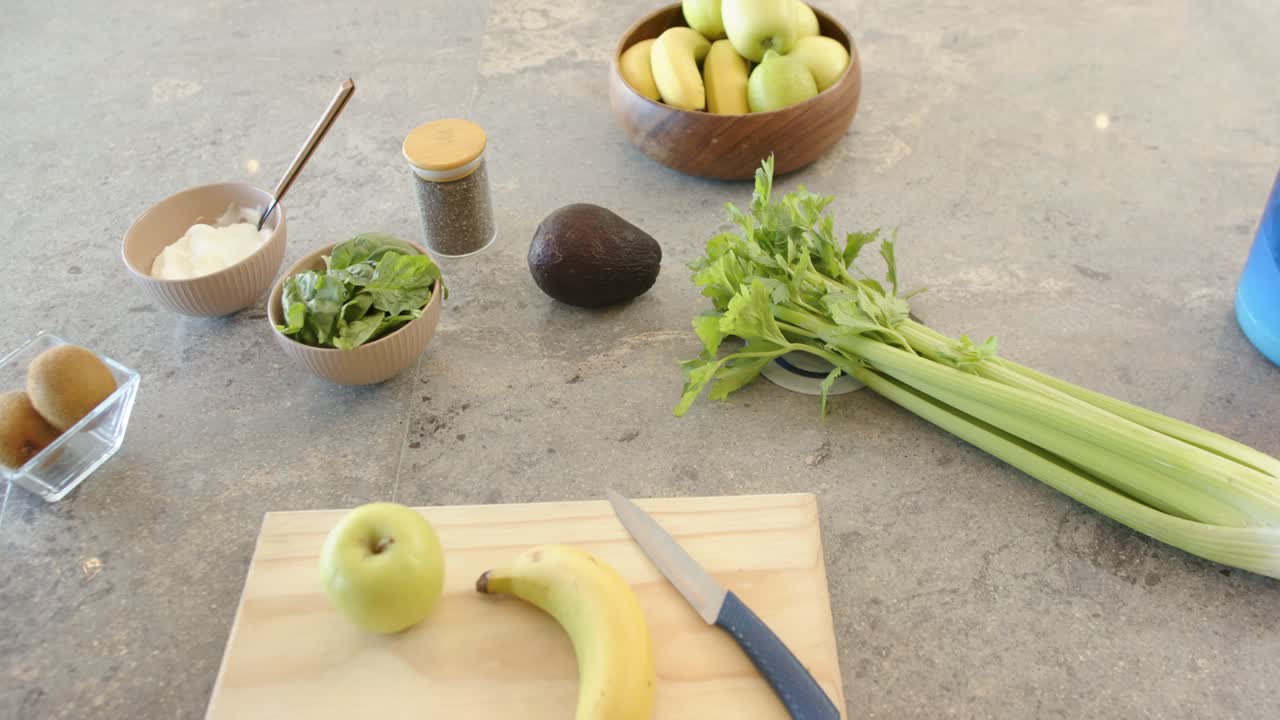 Camera is slowly panning while celery is staying centered on countertop, revealing prep ingredients