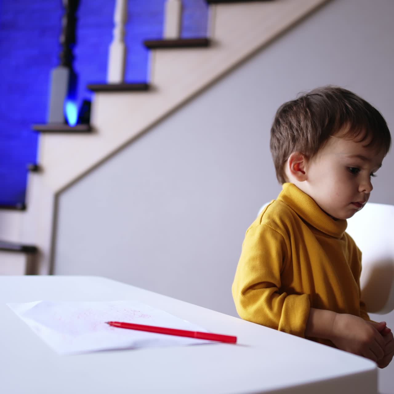 Adorabile e dolce bambino finisce di disegnare, posa la penna e vuole alzarsi. Il bambino si ferma improvvisamente e torna a disegnare.