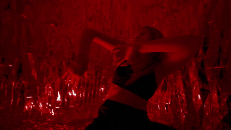 woman performing expressive contemporary dance in red flickering light