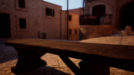 a wooden bench sits on a cobblestone street in a medieval village