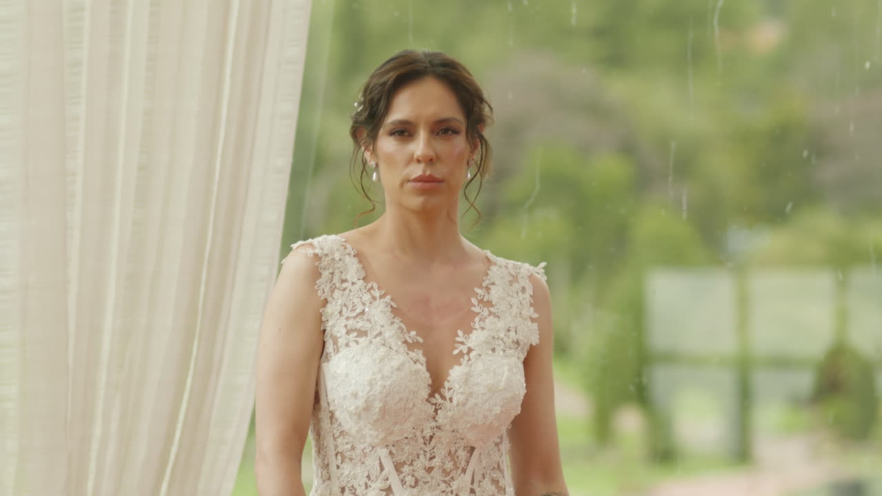 Medium shot of a bride walking with a bouquet of flowers, wearing a lace dress as she heads to the ceremony.