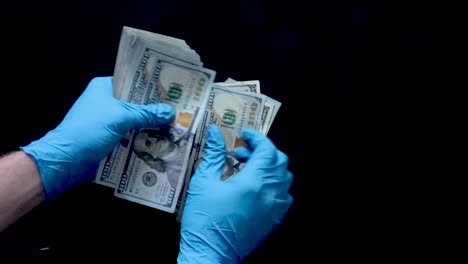 Nitrile-gloved-hands-counting-a-stack-of-benjamins-onto-a-black-surface-in-slow-motion
