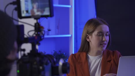 woman in a red blazer being interviewed in a studio setting.