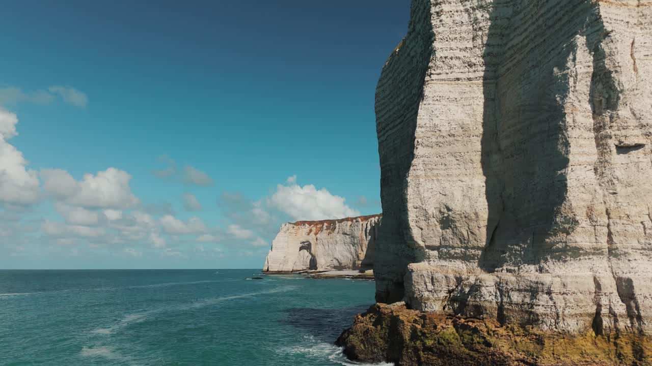 Drone fly-past of foreground cliffs revealing the natural arch of Étretat in Normandy, France