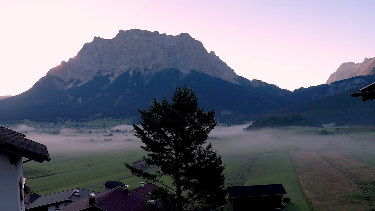 Sunrise at mount Zugspitze. Early morning in the Bavarian alps. Mist covers the valley floor until the sun rises over the ridge of the impressive peak of the mountain, flooding the valley with light.