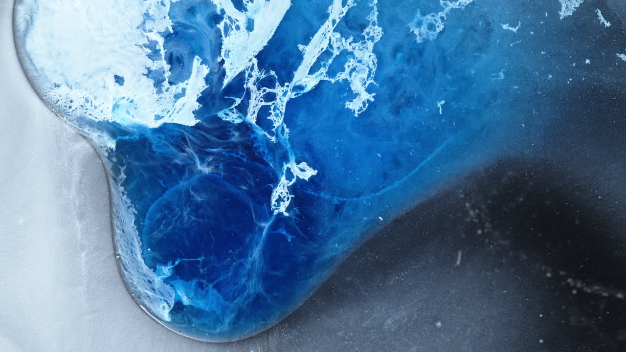 Ink mixing in water with macro shot of vibrant blue tones blending and swirling