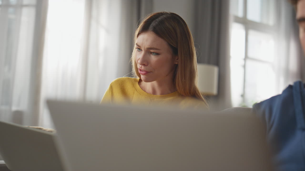 Closeup talking pair working laptops sitting sofa together. People communicating