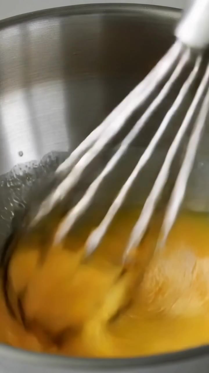 Pystysuuntainen video: Metallivispilä laskeutuu ja aloittaa hitaan pyöreän sekoituksen keittiökulhossa, sekoittaen munia.